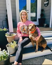 Breeder kneeling outdoors with two adult Catahoula Leopard Dogs in natural light